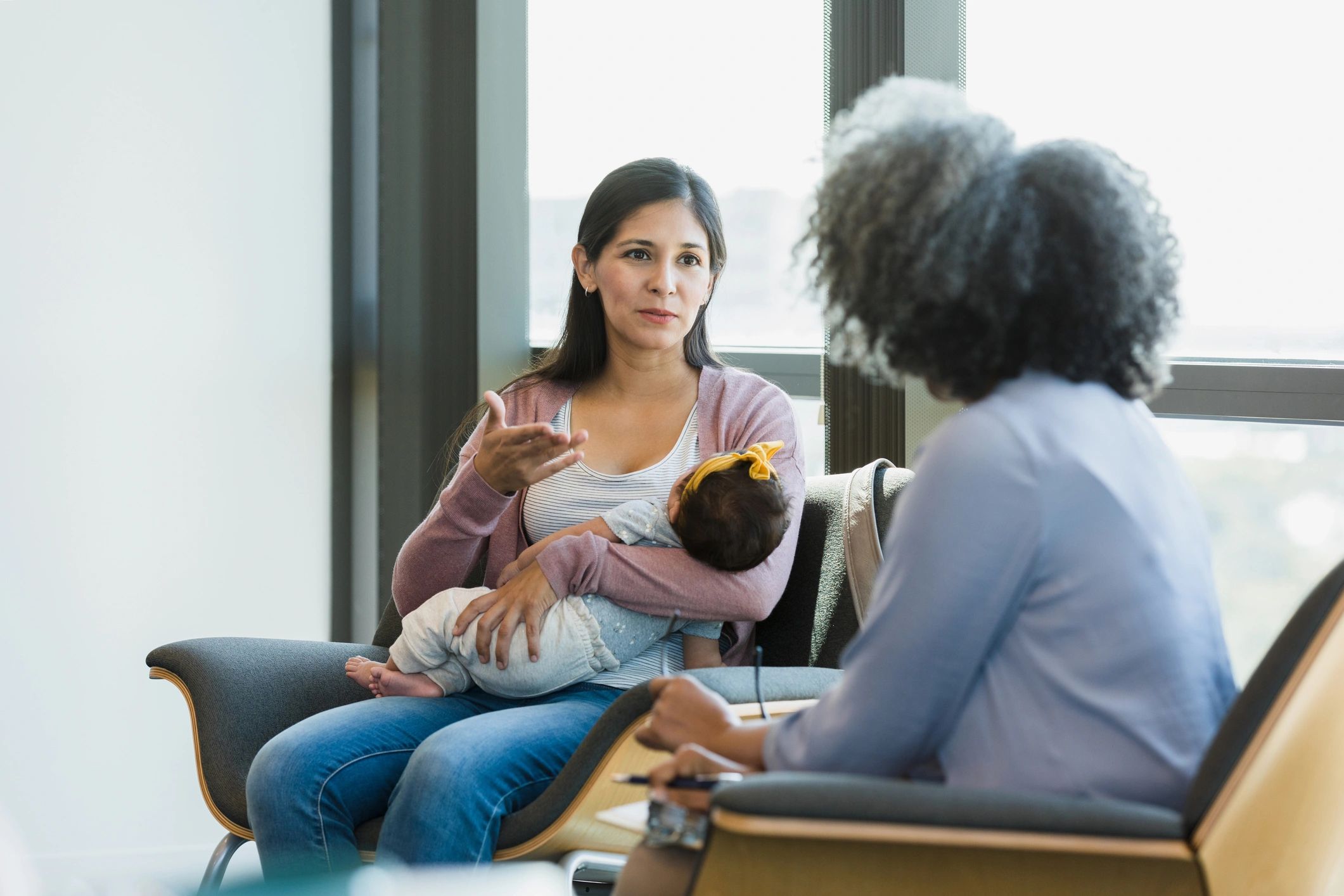 Parent holding baby while speaking with a supportive professional