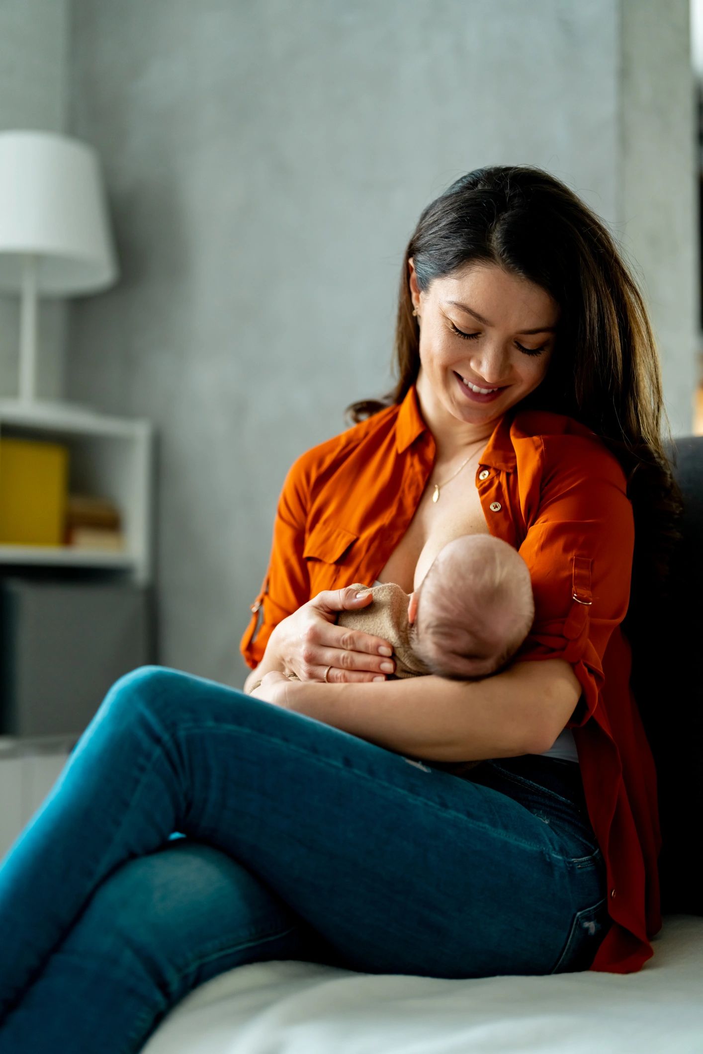 Mother breastfeeding her newborn with support nearby